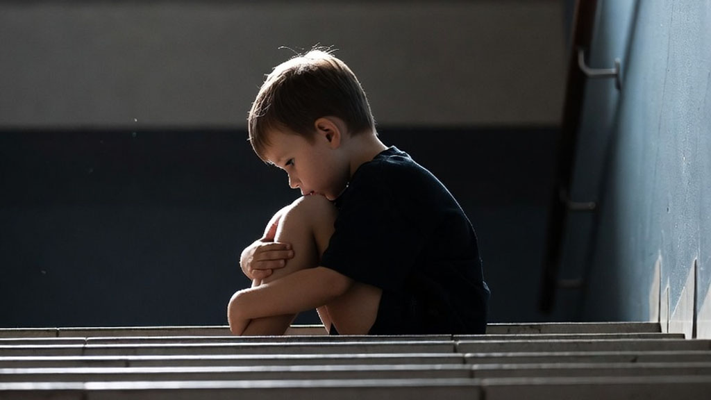 Child sitting alone on stairs during parental conflict in Texas divorce